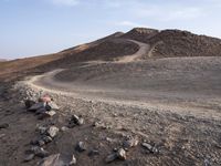 a truck on a dirt road in the desert with rocks and stones on the ground