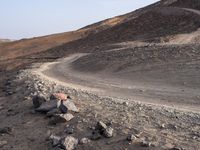 a truck on a dirt road in the desert with rocks and stones on the ground