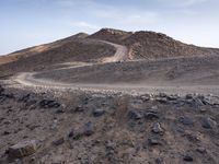 a truck on a dirt road in the desert with rocks and stones on the ground