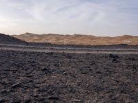 a truck on a dirt road in the desert with rocks and stones on the ground