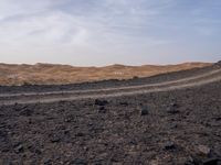 a truck on a dirt road in the desert with rocks and stones on the ground