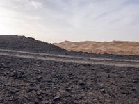 a truck on a dirt road in the desert with rocks and stones on the ground