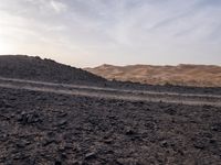 a truck on a dirt road in the desert with rocks and stones on the ground