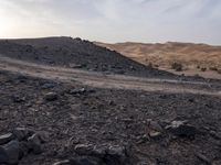 a truck on a dirt road in the desert with rocks and stones on the ground