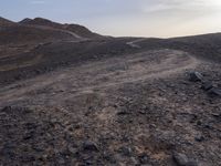 a truck on a dirt road in the desert with rocks and stones on the ground