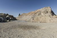 there is a bike rider on a paved dirt road through rocky area near a mountain