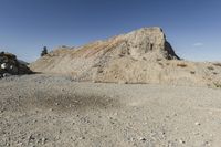 there is a bike rider on a paved dirt road through rocky area near a mountain