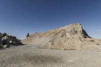 there is a bike rider on a paved dirt road through rocky area near a mountain