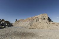 there is a bike rider on a paved dirt road through rocky area near a mountain