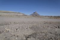 a dirt road is surrounded by some hills and desert like terrain as the vehicle sits on it