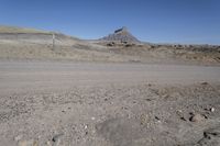 a dirt road is surrounded by some hills and desert like terrain as the vehicle sits on it