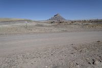 a dirt road is surrounded by some hills and desert like terrain as the vehicle sits on it