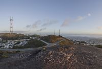 the view down the hill shows a winding road on either side of the valley leading to the city and the ocean