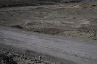 a dirt road in a barren landscape with gravel, rocks and dirt ground and a few rocks on either side