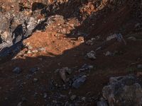 a man riding a horse on top of a steep hill near mountains covered with rocks