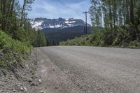 a car is on the side of an empty road with a mountain and sky in the background