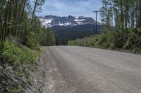 a car is on the side of an empty road with a mountain and sky in the background