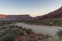 a mountain is seen as the sun sets over a desert plain in the distance is a large rocky mountain