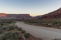 a mountain is seen as the sun sets over a desert plain in the distance is a large rocky mountain