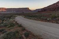 a mountain is seen as the sun sets over a desert plain in the distance is a large rocky mountain