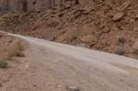 dirt roads leading through rugged mountainous terrain with steep cliffs in background and sign saying stop