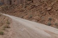 dirt roads leading through rugged mountainous terrain with steep cliffs in background and sign saying stop