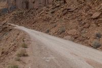 dirt roads leading through rugged mountainous terrain with steep cliffs in background and sign saying stop