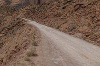 dirt roads leading through rugged mountainous terrain with steep cliffs in background and sign saying stop