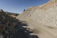 there is a bike rider on a paved dirt road through rocky area near a mountain