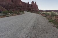 a dirt road running in the middle of a desert next to a rocky mountain range