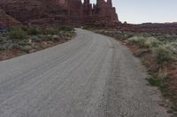 a dirt road running in the middle of a desert next to a rocky mountain range