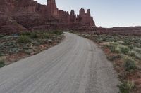 a dirt road running in the middle of a desert next to a rocky mountain range