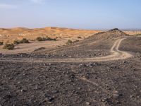 a truck on a dirt road in the desert with rocks and stones on the ground