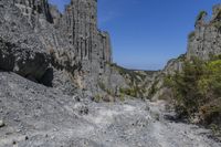 there are many rocks that have been eroded by the cliff side and some grass growing out on each one