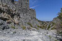 there are many rocks that have been eroded by the cliff side and some grass growing out on each one