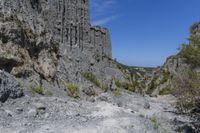 there are many rocks that have been eroded by the cliff side and some grass growing out on each one