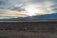 a lone fire hydrant on a deserted beach in the middle of nowhere, during sunset