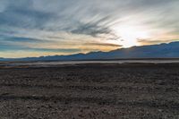 a lone fire hydrant on a deserted beach in the middle of nowhere, during sunset