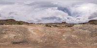 there is a dirt field and some clouds in the background of the landscape at desert area