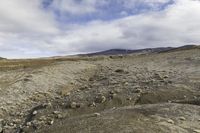 the dirt ground on the bottom of the mountain is barren and covered by rocks and moss