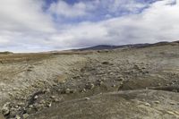 the dirt ground on the bottom of the mountain is barren and covered by rocks and moss