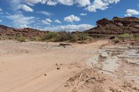 a dirt road with a truck parked on the side of it in a rocky area