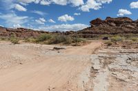 a dirt road with a truck parked on the side of it in a rocky area