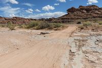 a dirt road with a truck parked on the side of it in a rocky area