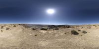 a fish eye view of a desert area with large rocks and bushes under a blue sky