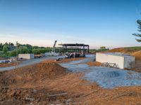 a picture of a building being built on a field near a forest in the background