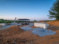 a picture of a building being built on a field near a forest in the background