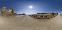 a street in the middle of a barren desert field with rocks and sun reflecting off of it