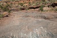 a woman standing in front of some rocks looking down on a bike ride through the wilderness