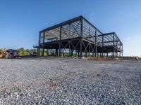 a picture of a building being built on a field near a forest in the background